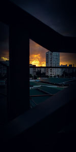 Silhouette bridge and buildings against sky during sunset