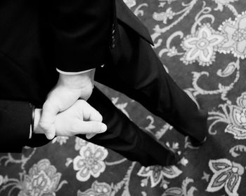 Rear view of man with hands behind back standing on carpet