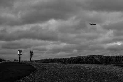 Woman standing at observation point against cloudy sky