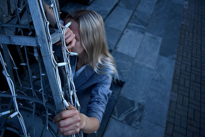 High angle view of woman crouching by gate outdoors