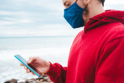 Midsection of man using mobile phone at beach