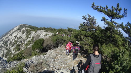 High angle view of hikers walking on mountain against clear sky