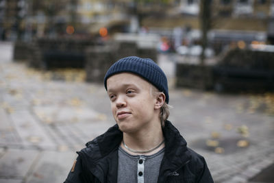 Portrait of young man looking away while standing on street in city