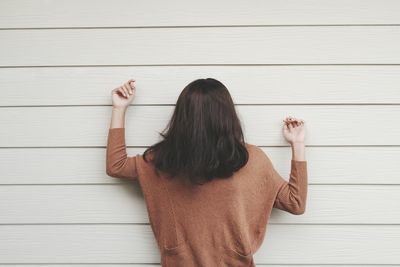 Woman with black hair standing against white wall