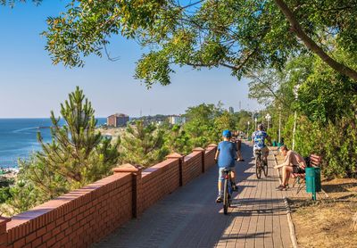 Rear view of people walking by sea against sky