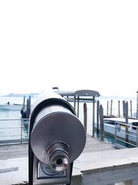 Close-up of coin-operated binoculars by sea against clear sky