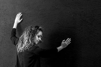 Side view of young woman standing against wall