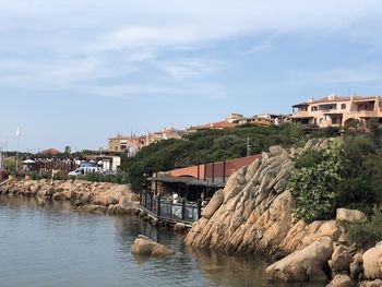 Buildings by river against sky