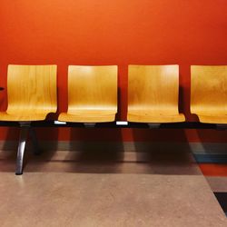 Empty chairs against orange wall