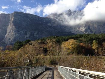 Footpath leading towards mountains against sky