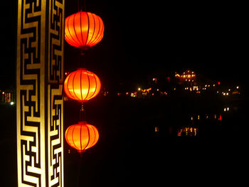 Illuminated lanterns hanging against sky at night
