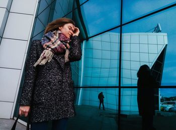 Young woman standing in front of glass window