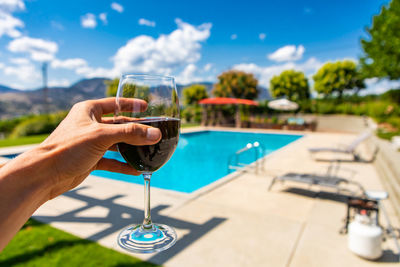 Hand holding drink at swimming pool