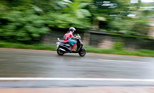 Man riding motor scooter on road