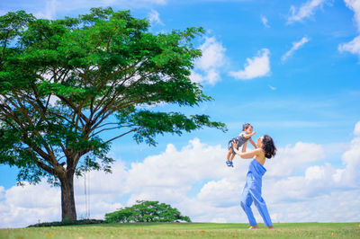 Full length of woman standing on field against sky