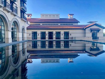 Buildings by swimming pool against blue sky