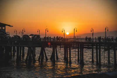 Silhouette pier over sea against sky during sunset