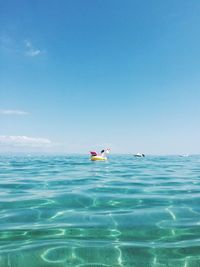 Person swimming in sea against blue sky