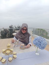 Woman holding ice cream cone on table against sky