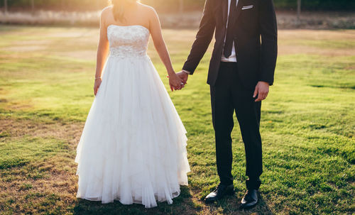 Low section of newlywed couple standing on land