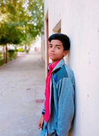 Boy looking away while standing against wall