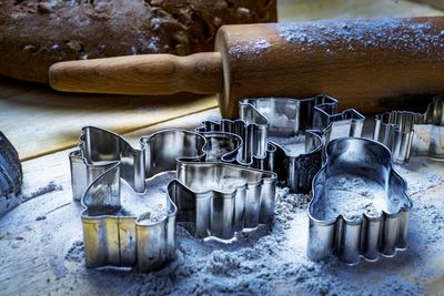 Close-up of pastry cutters with flour and rolling pin on table