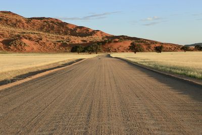 Road amidst field against sky