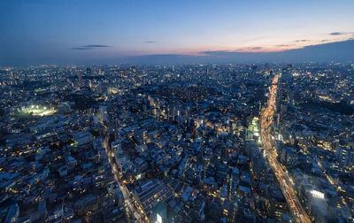 Illuminated cityscape against sky at dusk