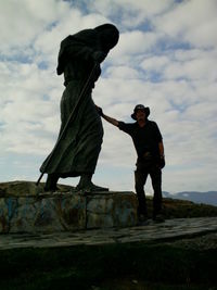 Man standing on rock against sky