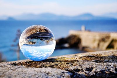 Close-up of crystal ball on beach against sky