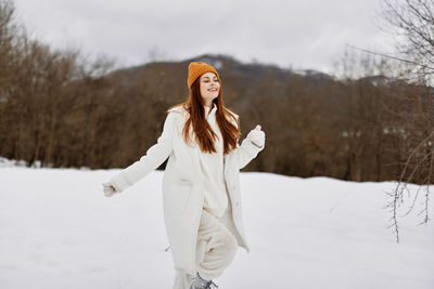 Happy woman walking on snow during winter