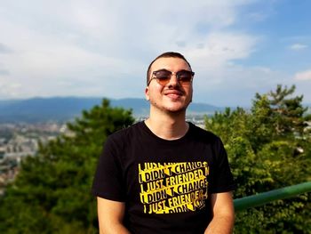 Portrait of young man wearing sunglasses standing against sky