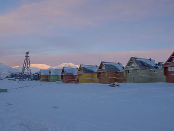 Built structure on snow against sky during sunset