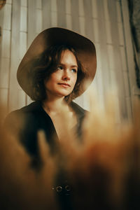 Portrait of young woman standing against wall