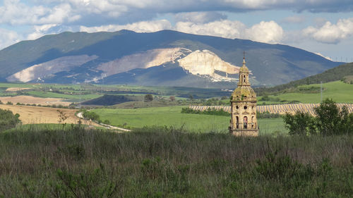 Built structure on field by mountains against sky