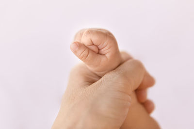 Close-up of baby hand over white background