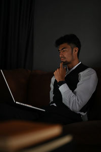 Man with hand on chin using laptop