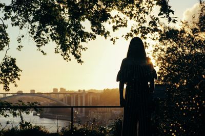 Rear view of silhouette woman in city against sky