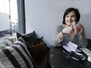 Smiling woman having drink at table in cafe