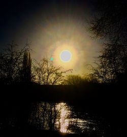 Silhouette trees by lake against sky during sunset