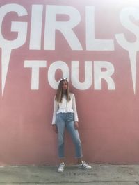 Full length portrait of woman standing against wall