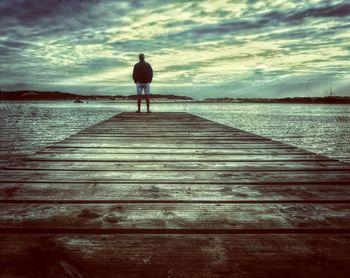 Rear view of woman standing on pier at beach