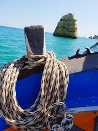 Rope tied on wooden post at beach against sky