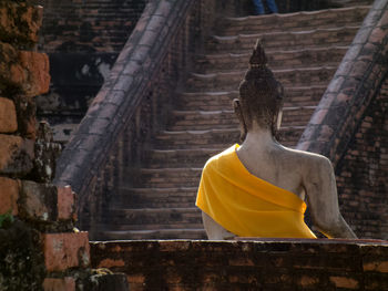 Buddha statue by wall outdoors