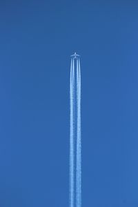 Low angle view of airplane emitting vapor trail against clear blue sky