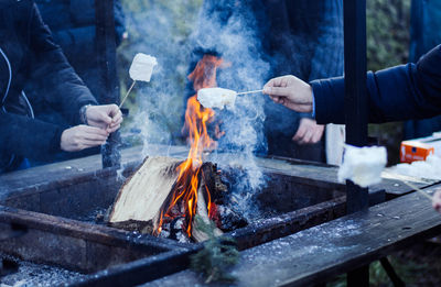Cropped image of people preparing food over barbecue grill