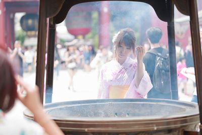 Woman in kimono by container at temple