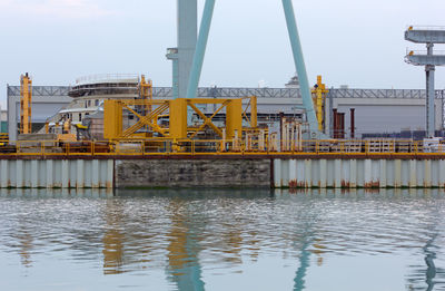 Construction site by river against sky