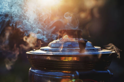 Beautiful atmospheric smoke and mist rising from an old samovar with setting sun on background