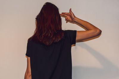 Rear view of woman standing against wall